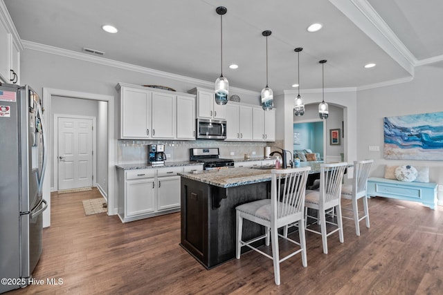 kitchen with white cabinets, appliances with stainless steel finishes, tasteful backsplash, and light stone counters