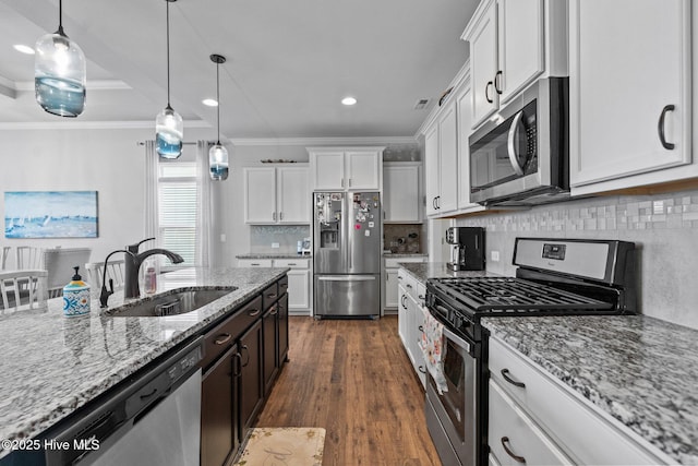 kitchen featuring decorative light fixtures, appliances with stainless steel finishes, white cabinetry, and a sink