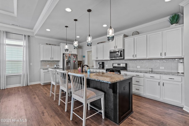 kitchen with crown molding, stainless steel appliances, a kitchen bar, backsplash, and white cabinetry