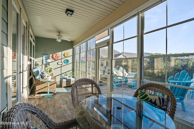 sunroom / solarium with a ceiling fan and outdoor dining space