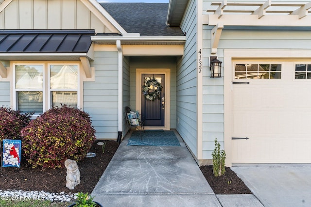 doorway to property featuring board and batten siding, an attached garage, and a shingled roof