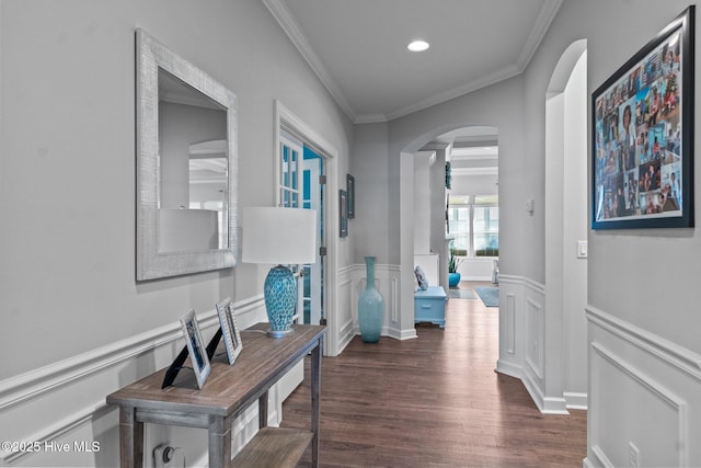 hall featuring arched walkways, ornamental molding, a wainscoted wall, and wood finished floors