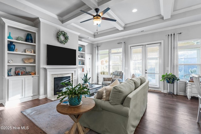 living room featuring beamed ceiling, a premium fireplace, a healthy amount of sunlight, and a ceiling fan