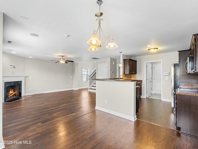 kitchen featuring dark brown cabinets, dark wood finished floors, dark countertops, and ceiling fan with notable chandelier