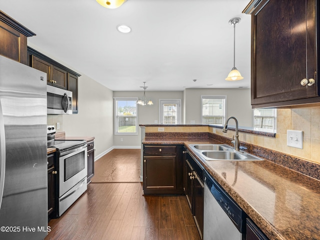kitchen featuring dark countertops, dark wood-style flooring, a sink, and appliances with stainless steel finishes