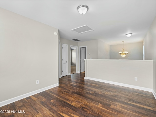 empty room featuring dark wood-type flooring, visible vents, baseboards, and attic access