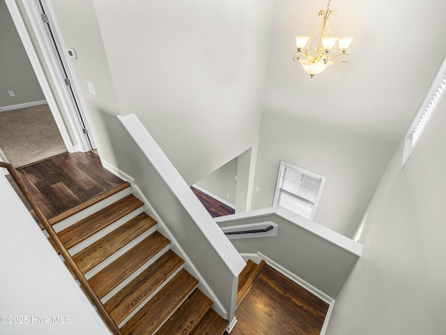 stairway featuring a chandelier, wood finished floors, and baseboards