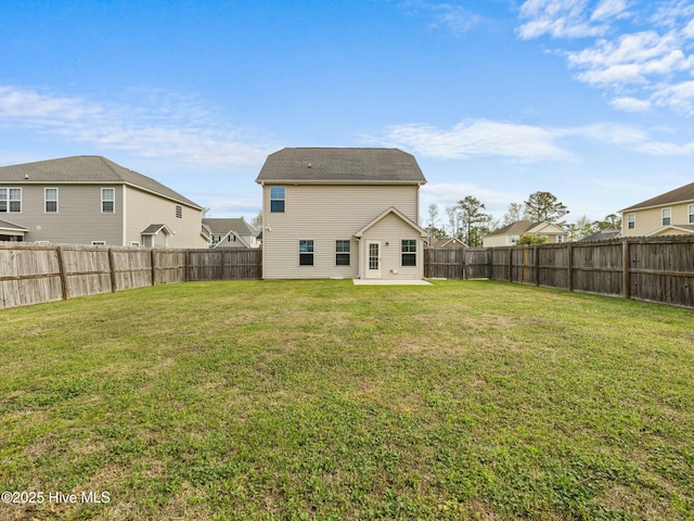 rear view of house featuring a fenced backyard and a lawn