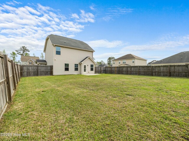 back of property with a fenced backyard and a lawn