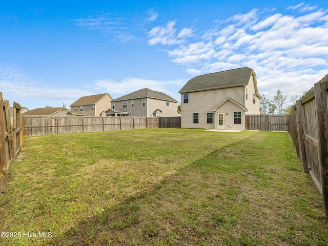 view of yard featuring a patio area, a fenced backyard, and a residential view