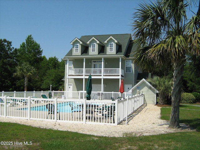rear view of property with fence, a fenced in pool, and a balcony