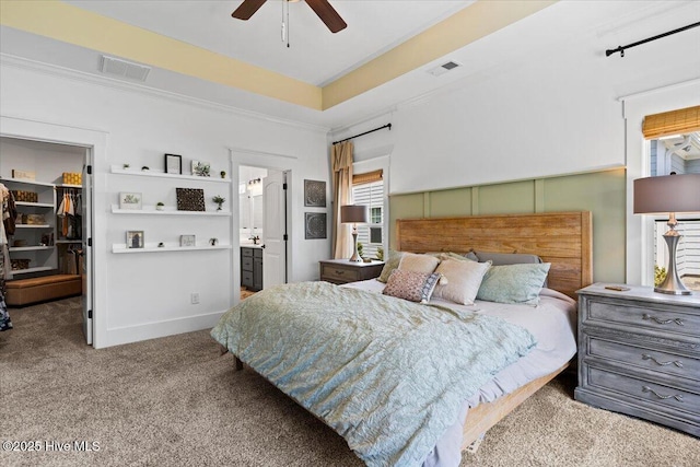 carpeted bedroom with a raised ceiling, ornamental molding, a spacious closet, and visible vents