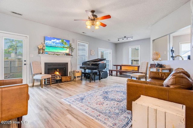 301 Softwood Ct, Jacksonville, NC 28540 - living room featuring a warm lit fireplace, a textured ceiling, a ceiling fan, visible vents, and wood finished floors