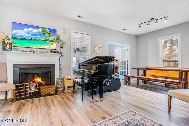301 Softwood Ct, Jacksonville, NC 28540 - living area with visible vents, a textured ceiling, a lit fireplace, and wood finished floors