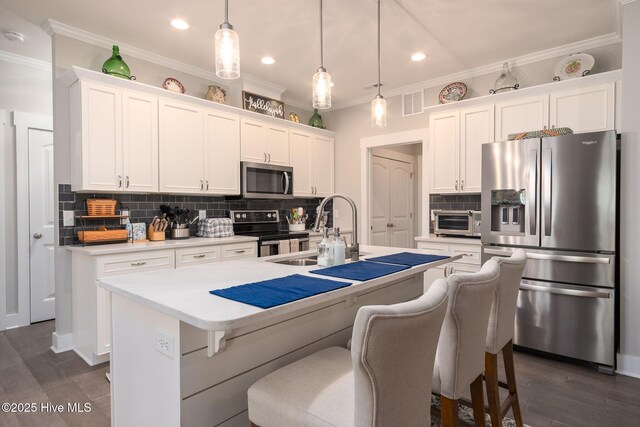 913 Wetherington Landing Rd, Stella, NC 28582 - kitchen with a sink, appliances with stainless steel finishes, white cabinetry, and a center island with sink