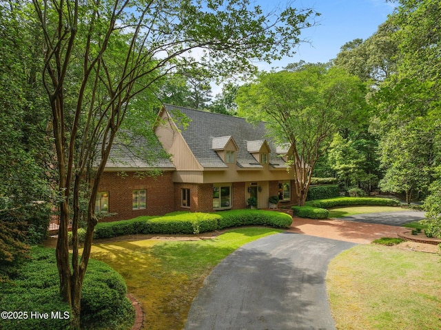 view of front facade featuring brick siding, a front lawn, and driveway