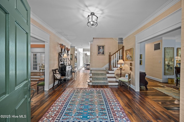 entrance foyer featuring crown molding, an inviting chandelier, baseboards, dark wood-type flooring, and stairway
