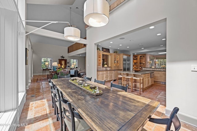 dining area featuring stone tile flooring, recessed lighting, baseboards, and a towering ceiling