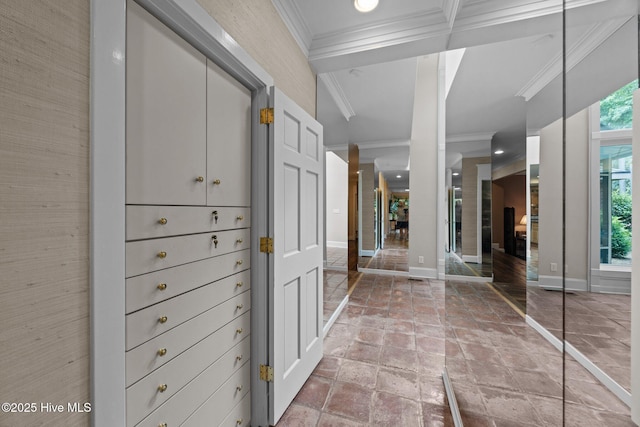 hallway featuring stone tile flooring, ornamental molding, and baseboards