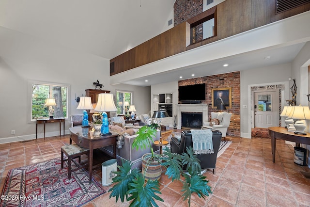 living area with baseboards, visible vents, a fireplace, and a towering ceiling