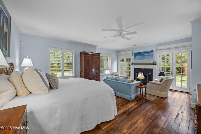 bedroom featuring access to outside, dark wood finished floors, a fireplace, and multiple windows