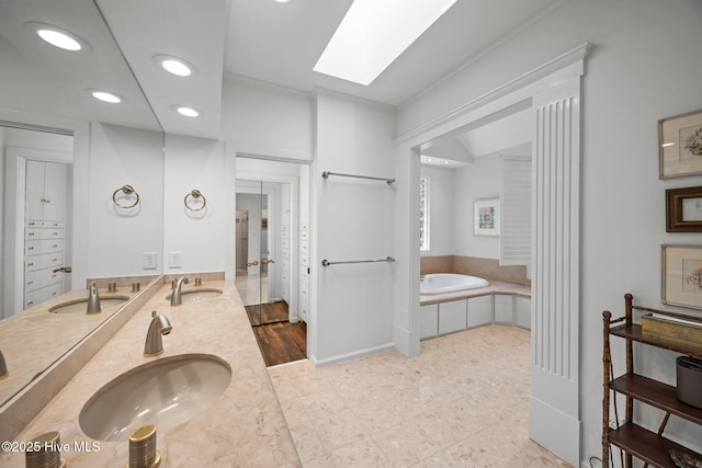 full bathroom with a sink, a skylight, and a garden tub