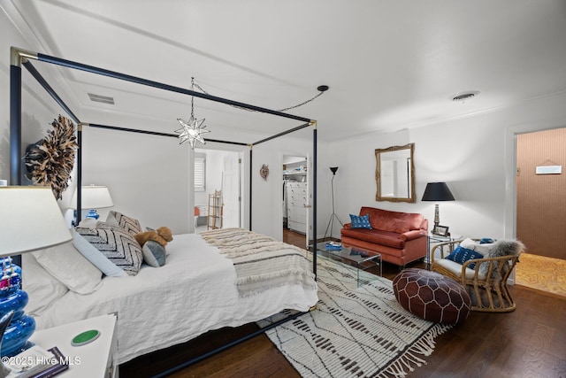 bedroom with crown molding, visible vents, and wood finished floors