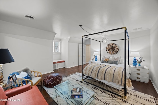 bedroom with baseboards, wood finished floors, and visible vents