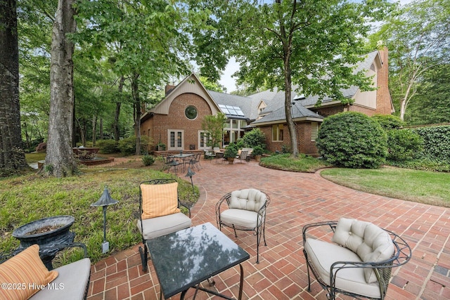 rear view of property with brick siding, a patio, a chimney, and outdoor dining space