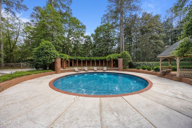 pool featuring fence, a patio, and a gazebo