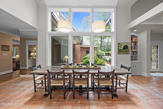 dining space with crown molding, baseboards, and a towering ceiling