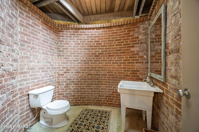 bathroom featuring toilet, brick wall, and wood ceiling