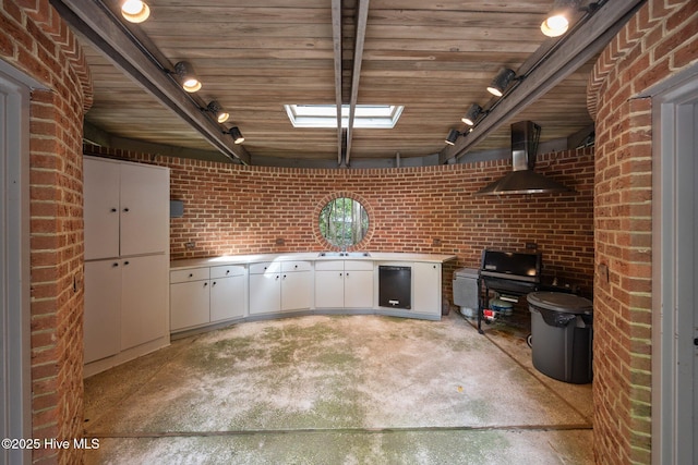 interior space featuring brick wall, track lighting, a sink, and refrigerator