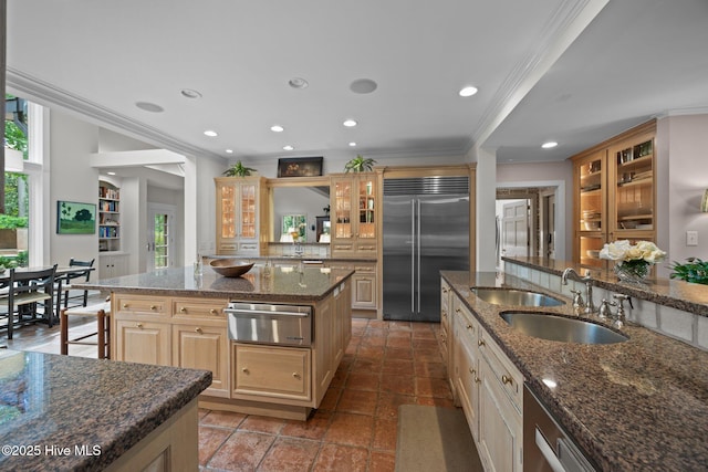 kitchen featuring a sink, glass insert cabinets, a warming drawer, ornamental molding, and stainless steel built in refrigerator