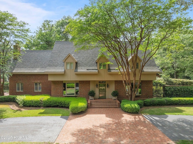 cape cod home with brick siding, fence, and a chimney