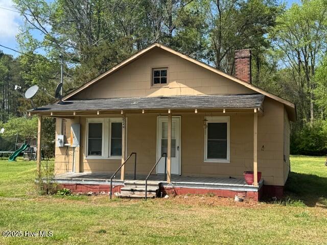 224 Millennium Rd # B, Aulander, NC 27805 - view of front facade with a shingled roof, a porch, a trampoline, a chimney, and a front lawn
