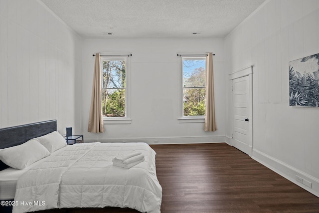 bedroom with a textured ceiling, baseboards, and wood finished floors