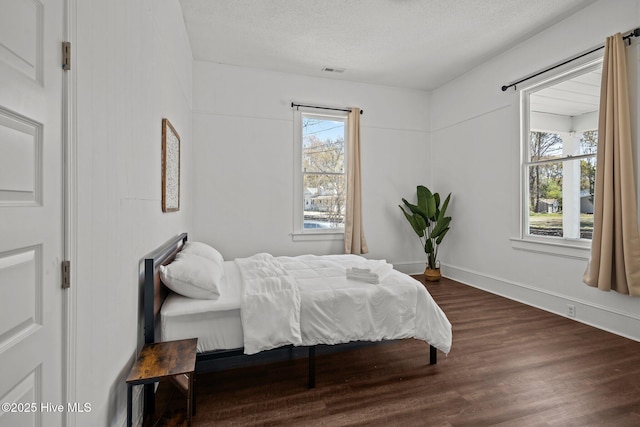 bedroom featuring visible vents, a textured ceiling, and wood finished floors