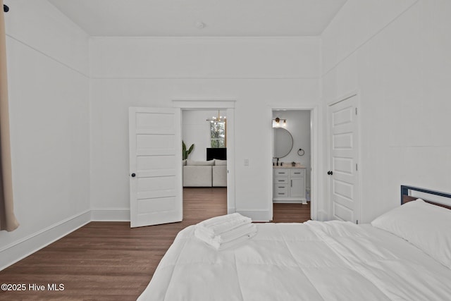 bedroom with ensuite bathroom, baseboards, a notable chandelier, and dark wood-style floors