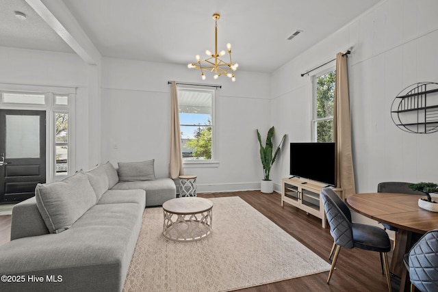 living area with plenty of natural light, visible vents, an inviting chandelier, and dark wood finished floors