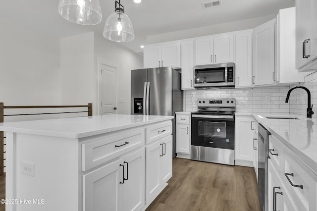 1205 Mackerel Ln Unit 2, Carolina Beach, NC 28428 - kitchen with light wood-type flooring, visible vents, decorative backsplash, stainless steel appliances, and a sink