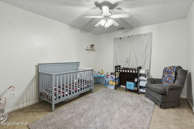 carpeted bedroom featuring a nursery area, visible vents, baseboards, and a textured ceiling