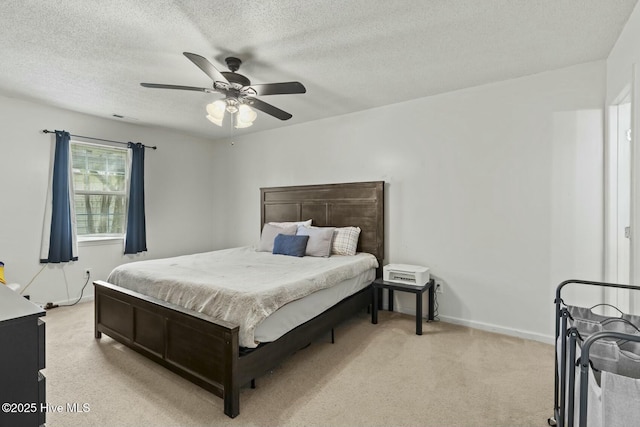 bedroom featuring visible vents, light colored carpet, baseboards, and a textured ceiling
