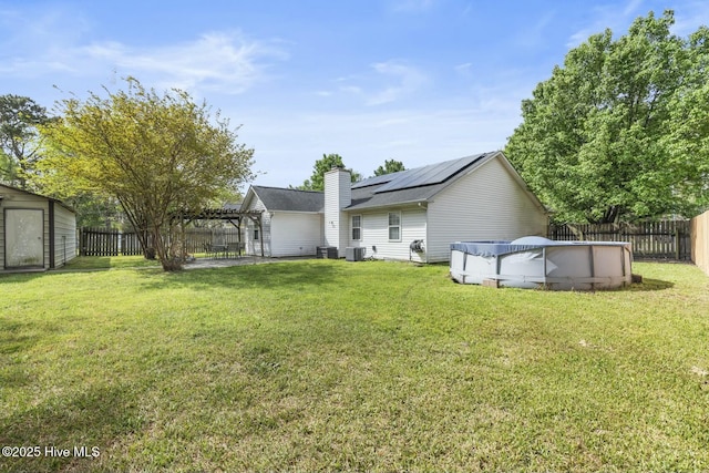 back of house featuring solar panels, a pergola, a lawn, a fenced backyard, and a fenced in pool