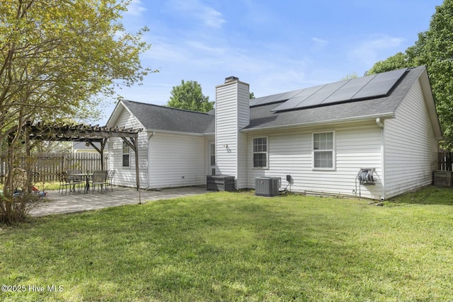 back of house featuring a pergola, a patio area, central AC, fence, and roof mounted solar panels