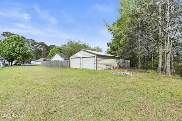 view of yard with a detached garage, fence, and an outdoor structure