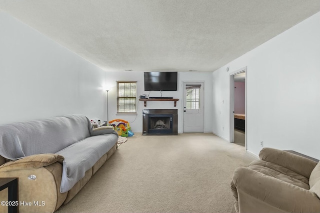 living room with light carpet, a fireplace with flush hearth, a textured ceiling, and baseboards