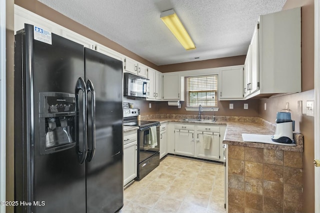 kitchen featuring a textured ceiling, light tile patterned flooring, white cabinets, black appliances, and a sink