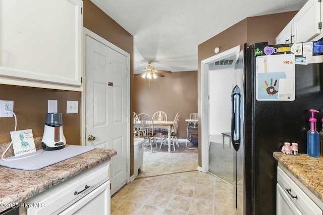 kitchen featuring freestanding refrigerator, white cabinets, a ceiling fan, and a textured ceiling