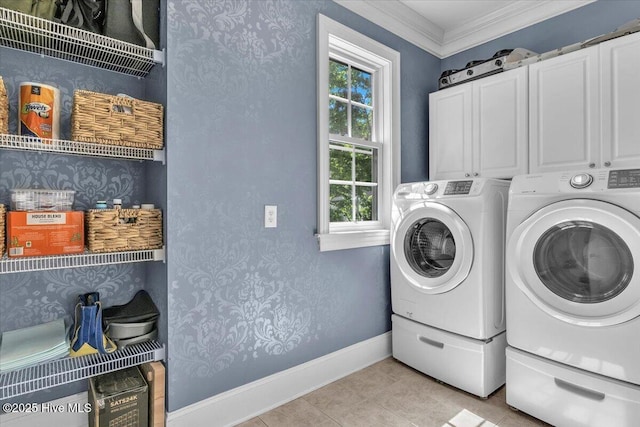 laundry area with baseboards, crown molding, light tile patterned flooring, cabinet space, and washing machine and clothes dryer